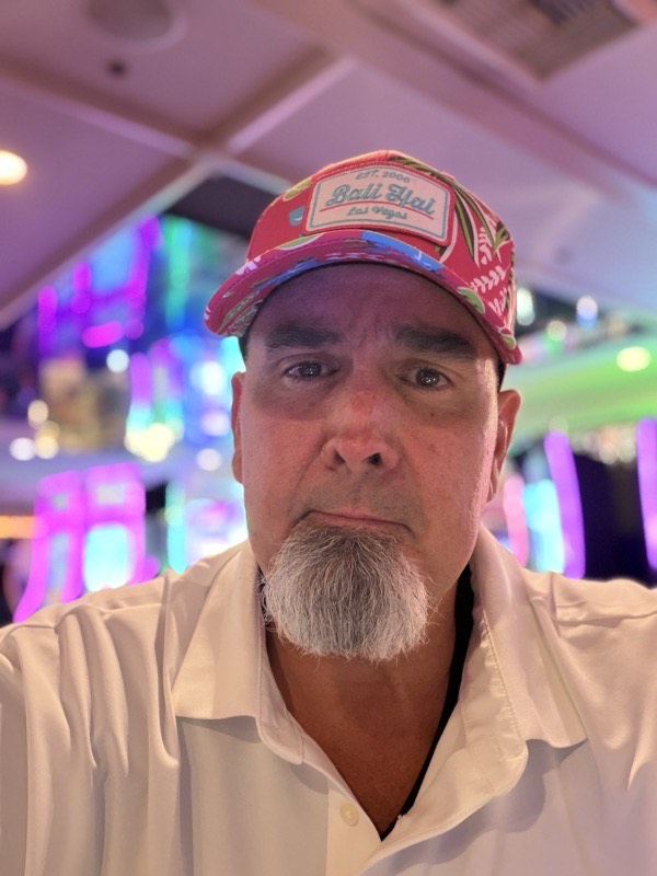 A selfie in a floral cap under casino neon.
