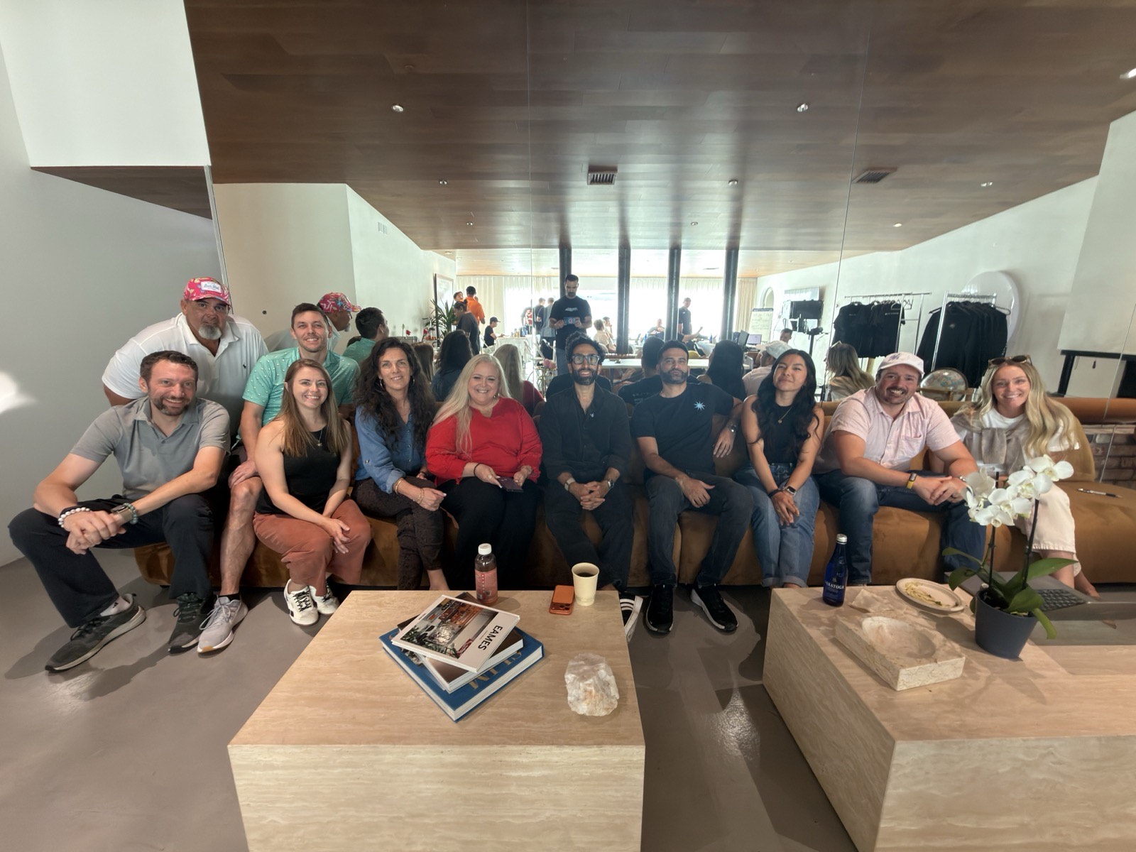 About a dozen people seated together across couches in a bright modern lounge, posing for a group photo.